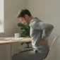 Oseba, ki se drži za križ med sedenjem za mizo