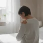 Oseba se med jutranjo rutino drži za boleče ramo